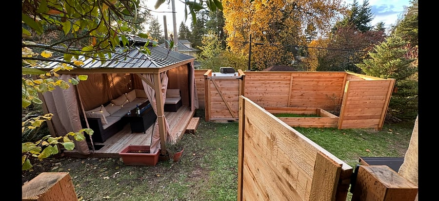 Fully fenced in section of backyard with Gazebo, patio furniture, and fire table