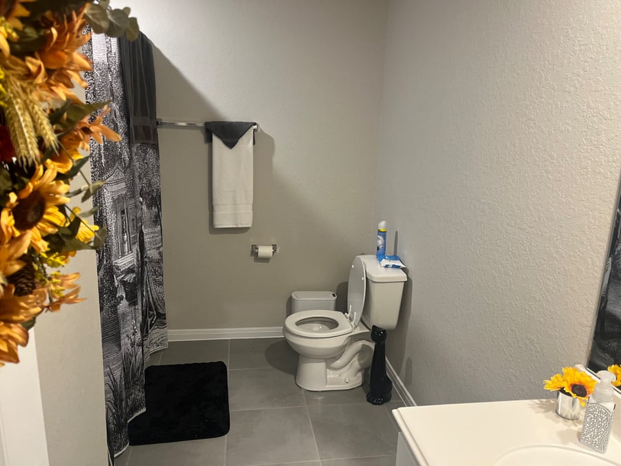 bathroom between two rooms, tub, shower, toilet paper, hand soap, shampoo, conditioner, body wash, towels, and washrags. 