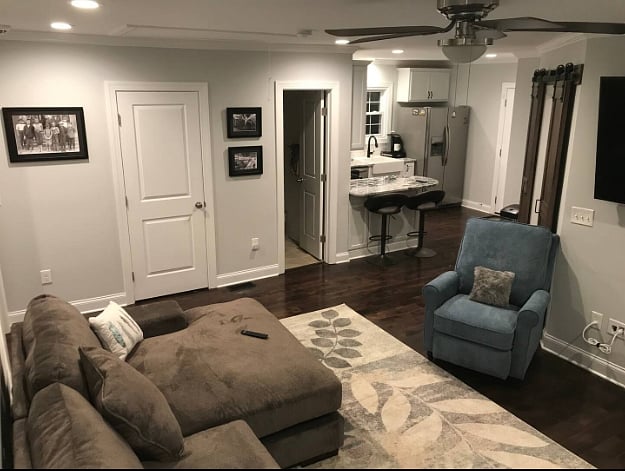 Living room with large wall mounted TV, sight lines into the kitchen, door open into hallway bath, closed door houses stackable washer/dryer.