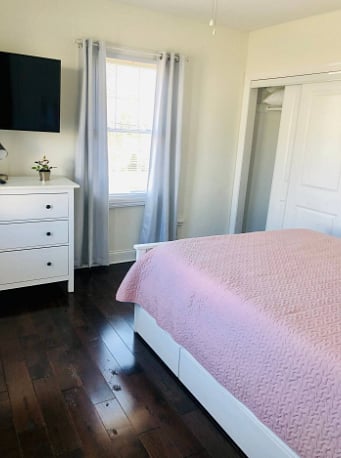 Queen bedroom (bedroom 2) off living room, wall mounted TV.