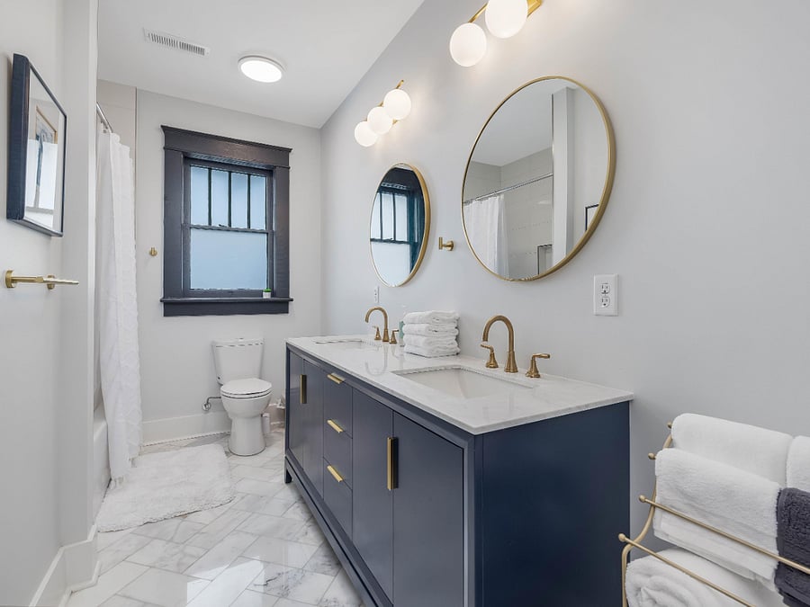hall bath with oversized tub/shoer combo and two sinks, marble floors