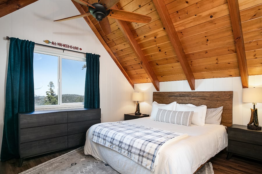 Upstairs, primary bedroom with king-sized bed and vaulted ceilings
