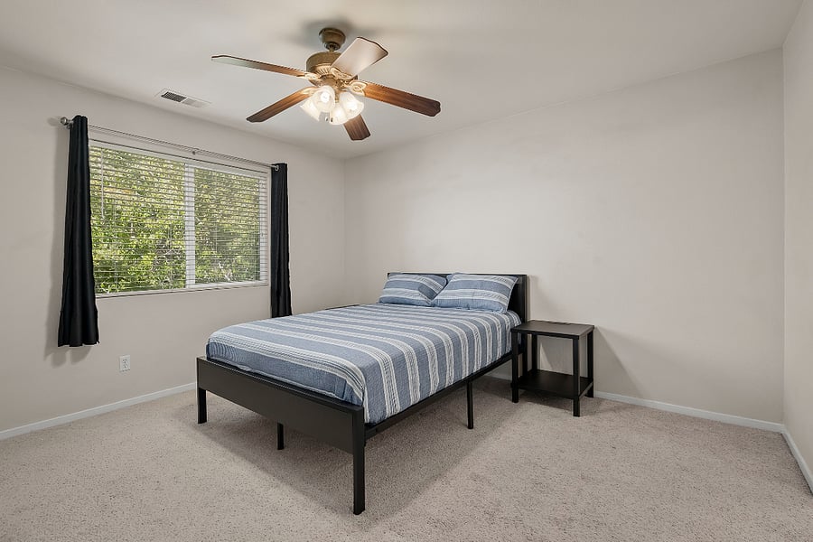 Master bedroom with blackout curtains and a nice view of the backyard and desert hillside.