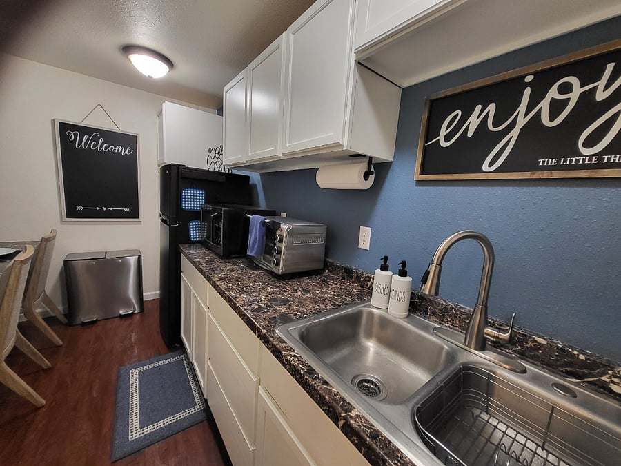 Basement Kitchenette with double sink, full sized refrigerator, microwave, toaster oven, coffee pot, electric kettle.