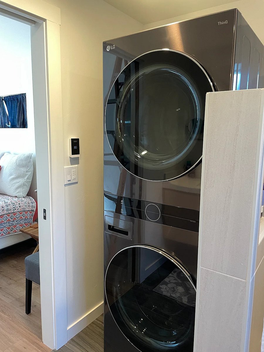 You have a brand new thinQ LG washer dryer along with an ironing board and iron, all conveniently located in the bathroom.
