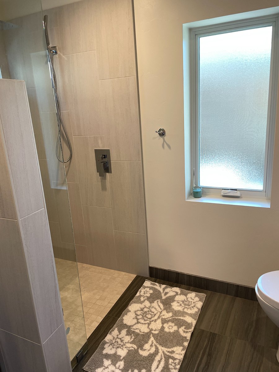 Walk-in shower with handheld and rain shower head.