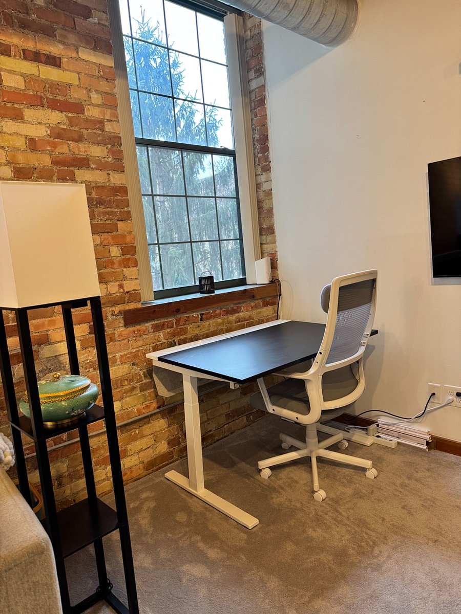Desk & chair in front room, facing south, view of courtyard/nature park