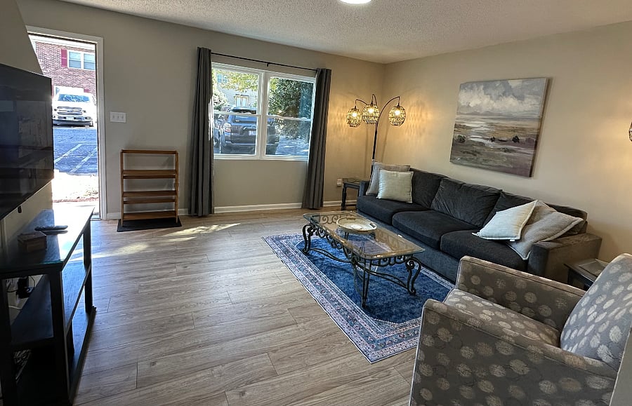 Sofa, chair, smart TV and shoe rack at door.