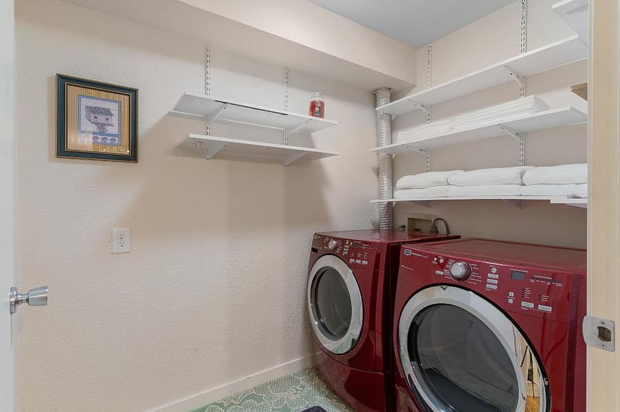 Laundry room with full size washer and dryer. Plenty of shelf space for all your needs. The door to the laundry room can be closed.