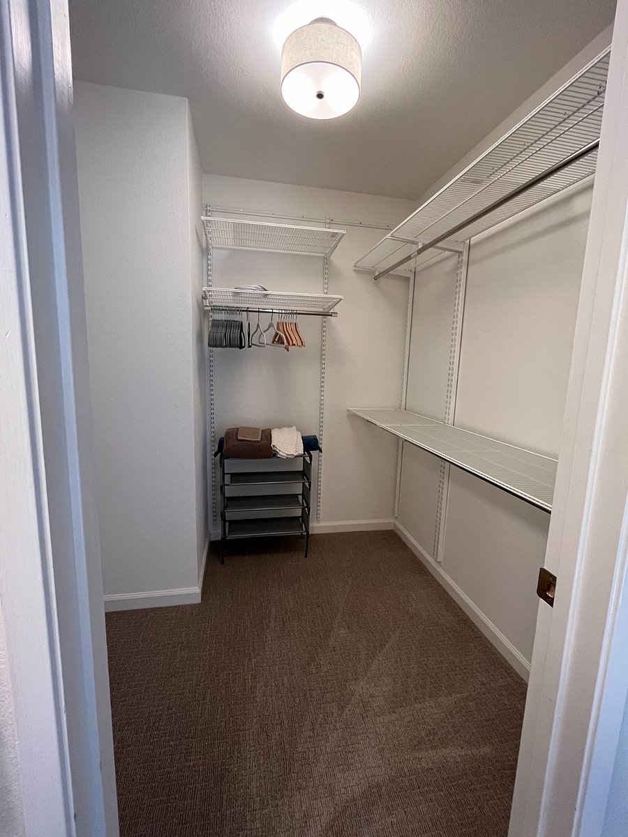 Large walk-in closet has plenty of room to hang clothes and also extra storage.
