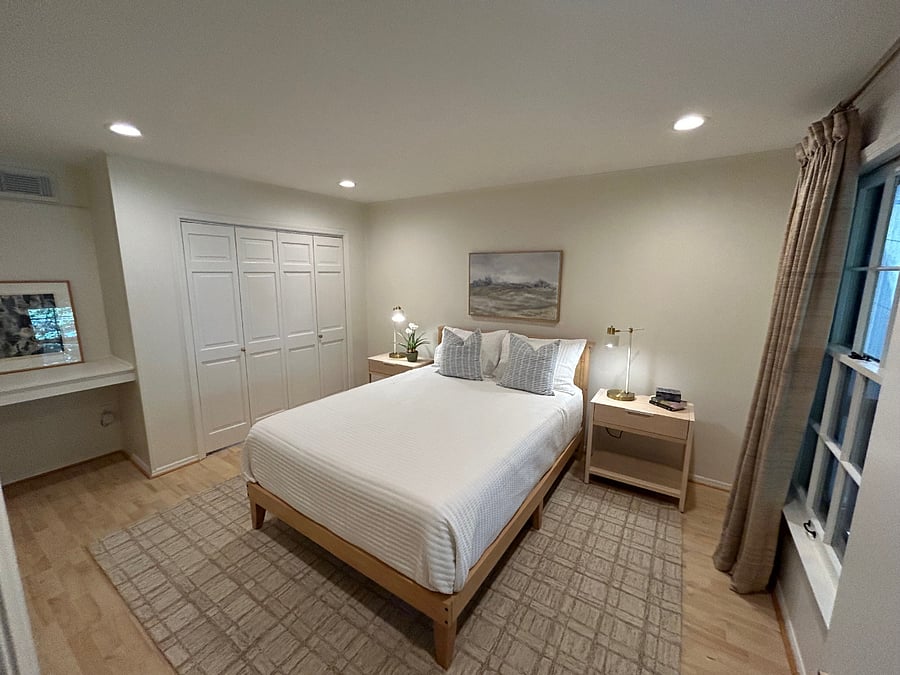 Bedroom with blackout curtains, large walk in closet, and built-in desk overlooking wooded backyard
