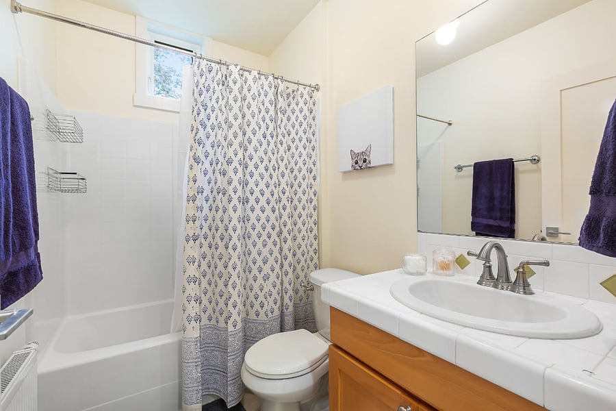 The downstairs bathroom is near both bedrooms and the dining room. There is storage within and a small cabinet outside for additional towels and bathroom supplies.