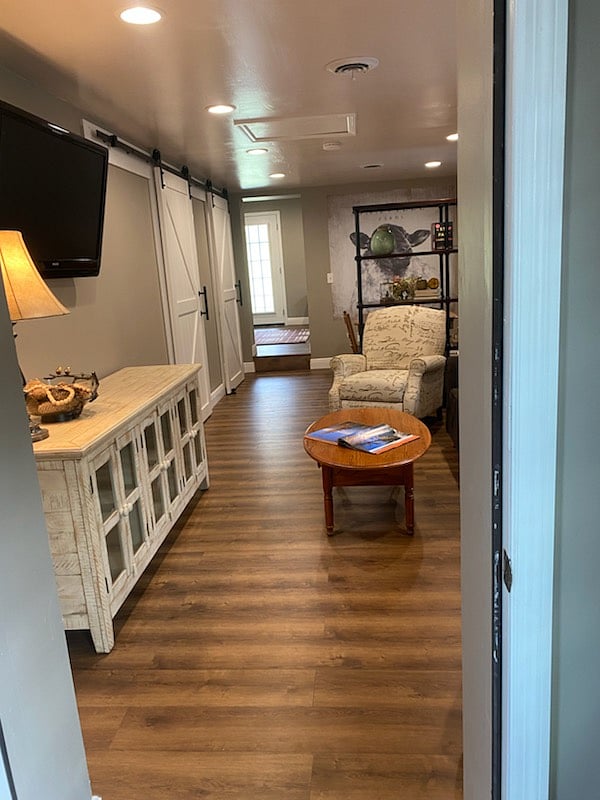 Great living room that has comfort, while incorporating a large TV, extra storage, reclining chairs, and a cozy couch.