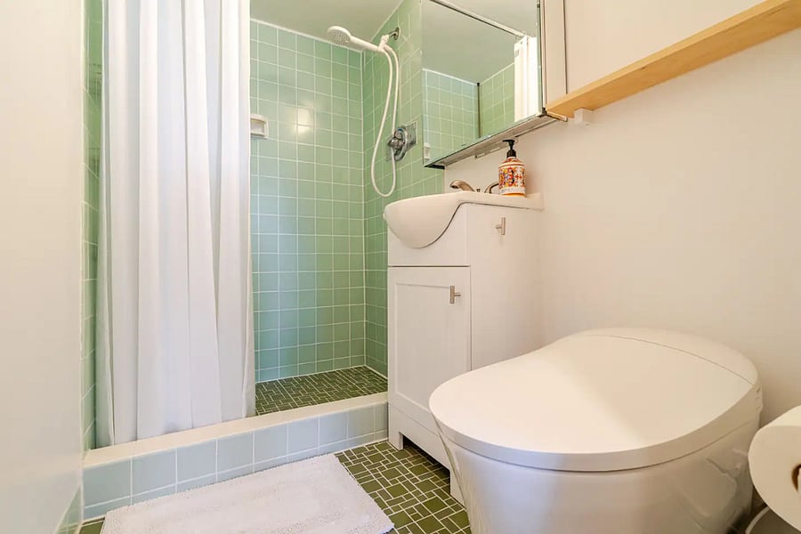 Renovated bathroom with floor-to-ceiling mint tile, walk-in shower, and smart toilet.