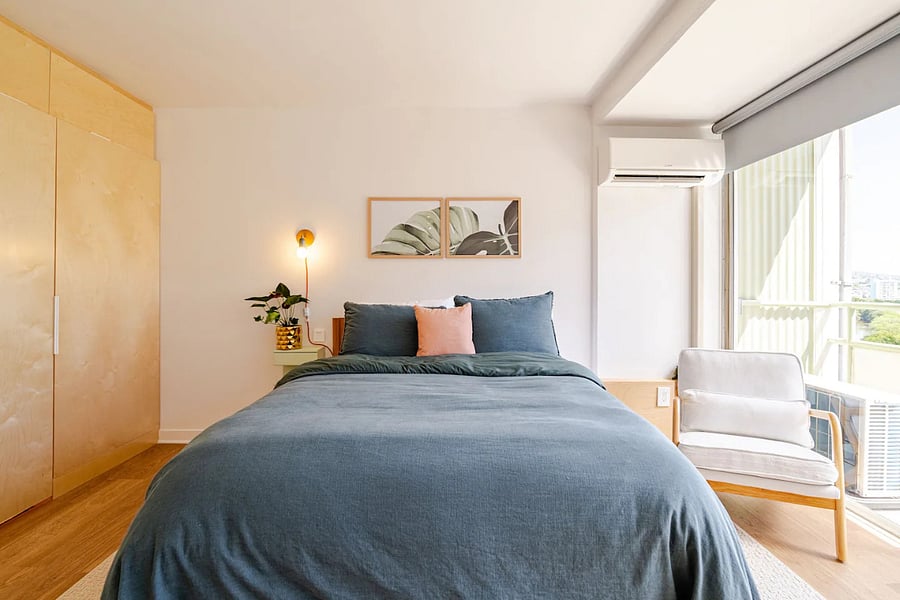 Queen bed, birch wardrobe, and armchair by the lanai, light-filled and calm.