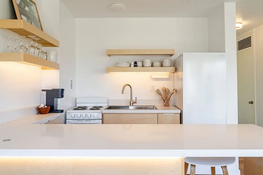 Kitchen view from the island. Quartz counters, stainless sink, open shelving, and Nespresso included.