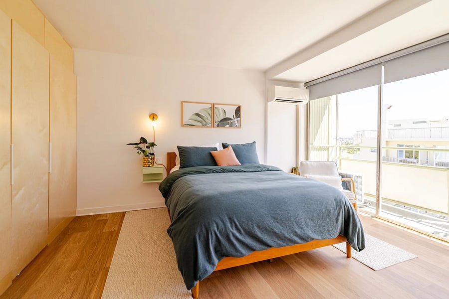Queen bed with motorized shades, split AC, custom birch wardrobe, and sliding glass door to the lanai.
