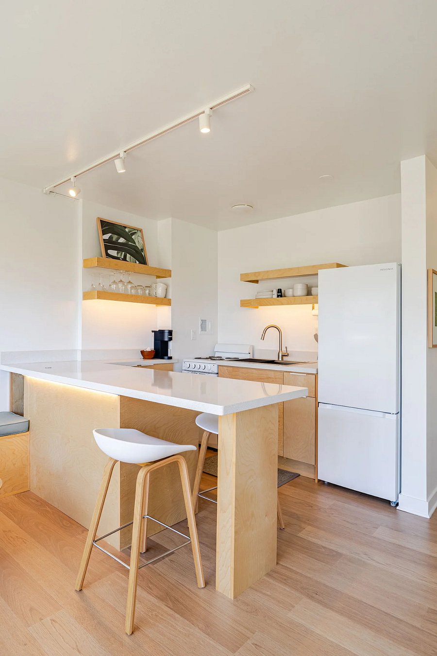 Kitchen with island seating for two, full-size fridge, and open shelving. Bright and functional.
