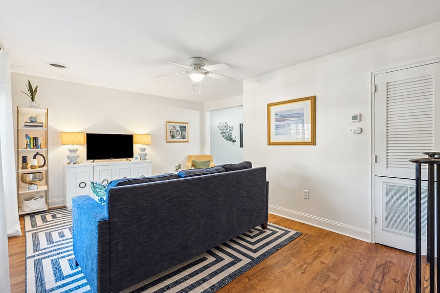 With an abundance of natural light from the large front windows, the open concept living room includes a cozy couch, arm chair, and Roku smart TV.