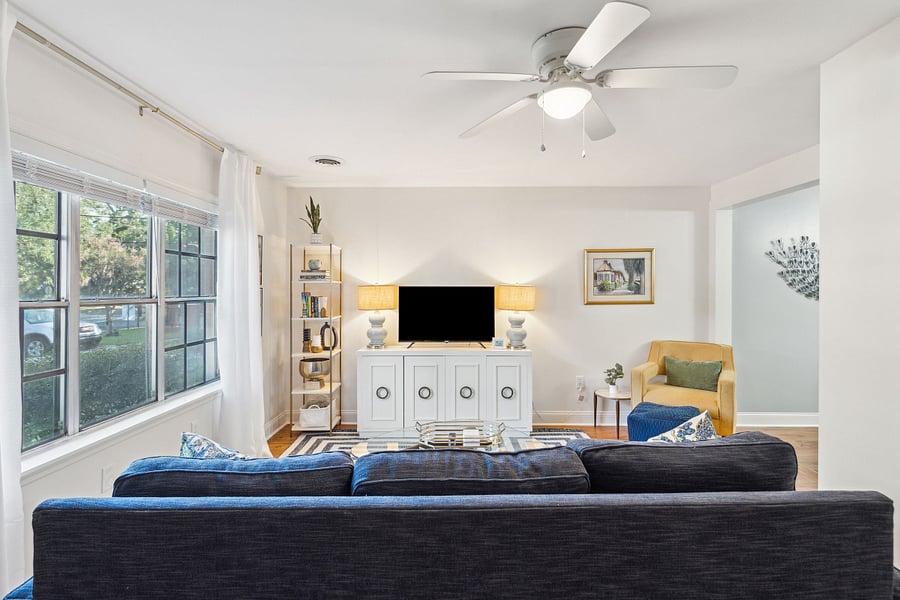 With an abundance of natural light from the large front windows, the open concept living room includes a cozy couch, arm chair, and Roku smart TV.