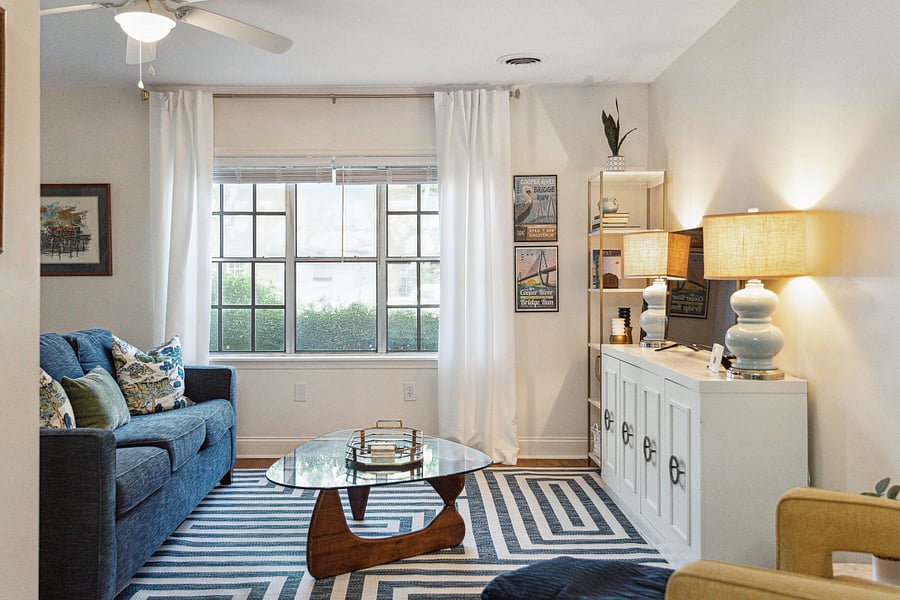 With an abundance of natural light from the large front windows, the open concept living room includes a cozy couch, arm chair, and Roku smart TV.
