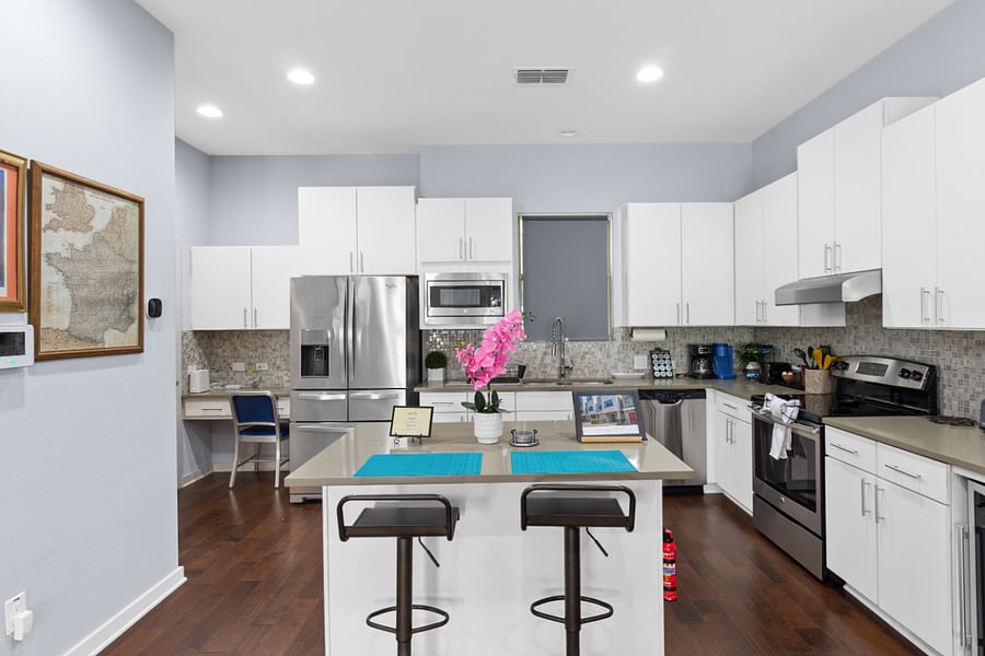 Pull up a stool at the spacious kitchen island for breakfast or a morning espresso. Features modern white cabinetry, stylish mosaic tile backsplash, and beautiful hardwood floors.