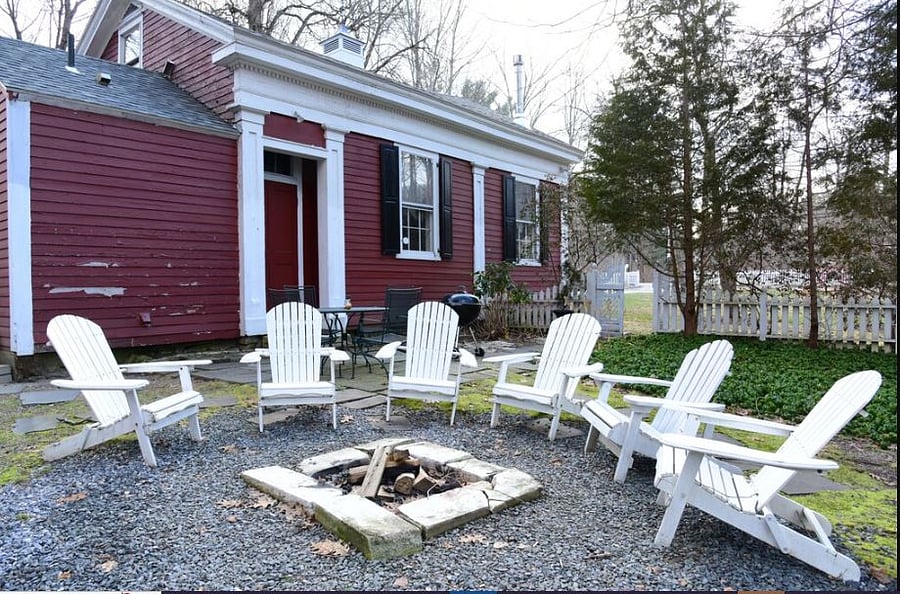 Side yard garden with table, chairs and easy chairs by  fire pit and brook below.