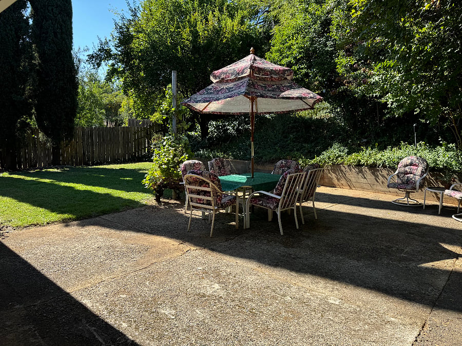 Large patio with table and chairs in the wooded rear yard.