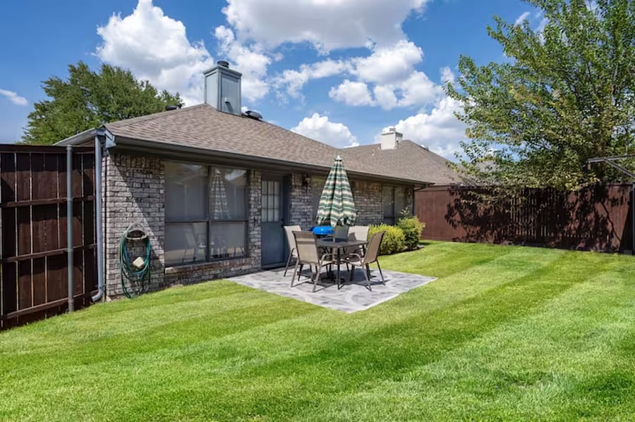 The backyard is spacious and also has an ample green space behind the back fence for pets to have added space to play. Fully fenced, with dining table, chairs, and grill.