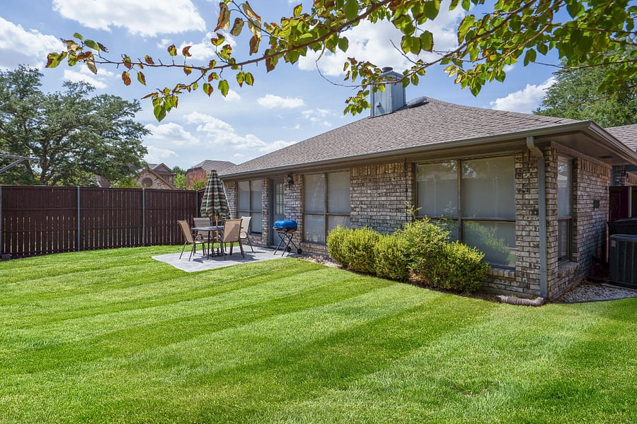 The backyard is fully fenced with an 8 ft privacy fence, patio with an outdoor dining set and grill.
