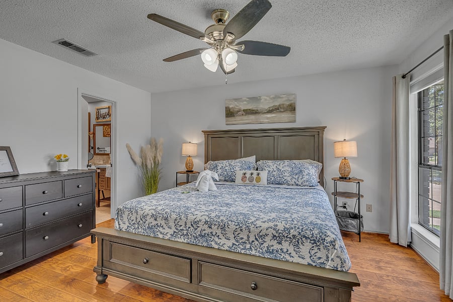 Primary bedroom with king bed, ensuite with walk-in tiled shower, dresser, chest of drawers, nightstands, TV, ceiling fan, and large walk-in closet.
