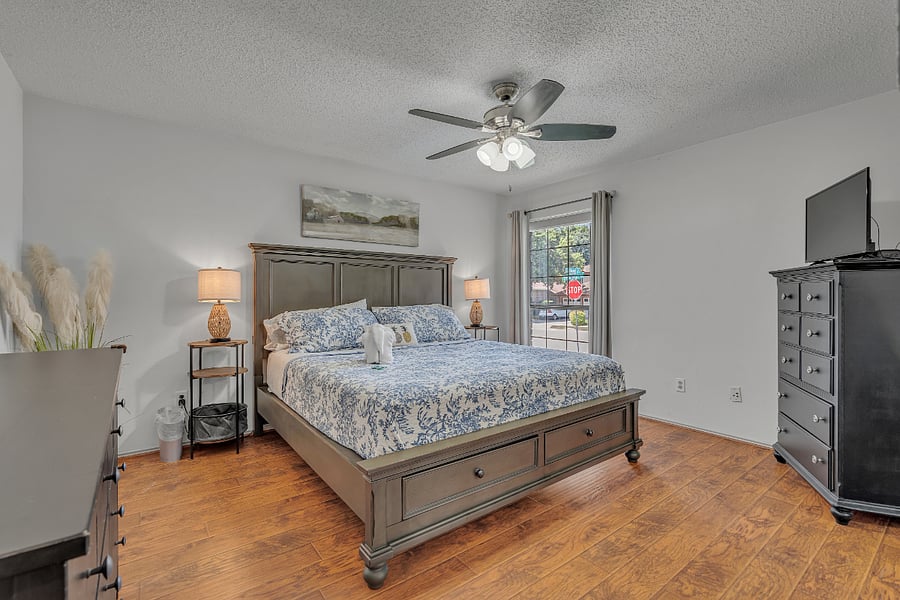 Primary bedroom with king bed, ensuite with walk-in tiled shower, dresser, chest of drawers, nightstands, TV, ceiling fan, and large walk-in closet.