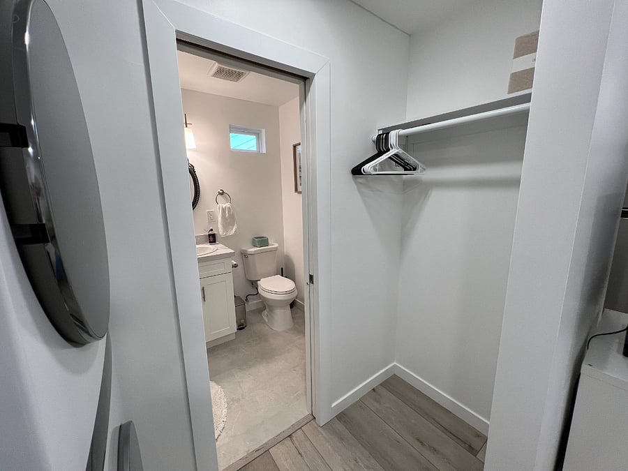 Closet with storage across from the washer/dryer. The bathroom is separated by a sliding pocket door for privacy and blocking light from the bathroom window.