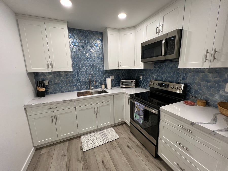 Full kitchen with range, microwave, toaster oven, refrigerator, ample cabinet storage, plates, bowls, eating and cooking utensils, pots and pans, and a large sink with storage for a drying rack and cutting board. The entire studio uses filtered water that is safe to drink.