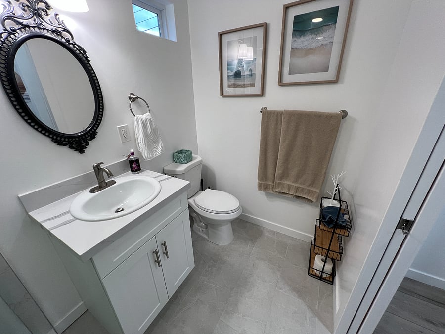 Bathroom with mirror, sink and vanity with storage, towel and hand towel bars, and extra storage for toiletries.