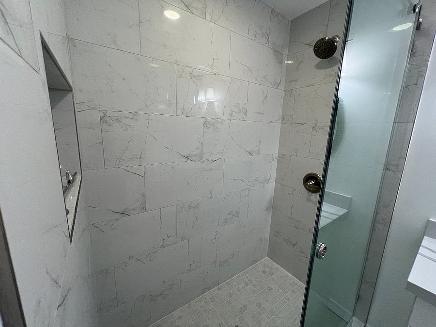 Spacious shower with cutout for shampoos and soaps. Sliding glass doors for ease of access.