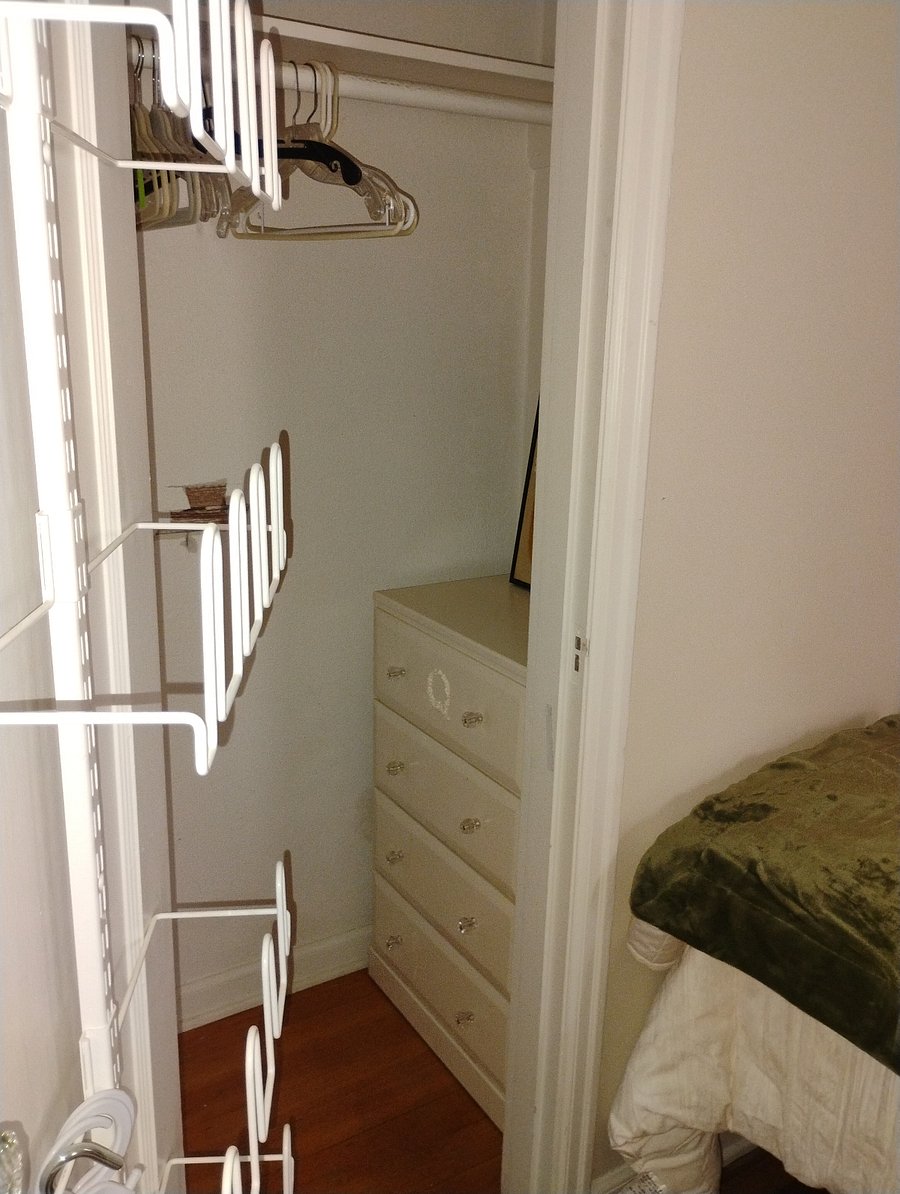 Walk in closet with hidden dresser and hanging shoe rack.