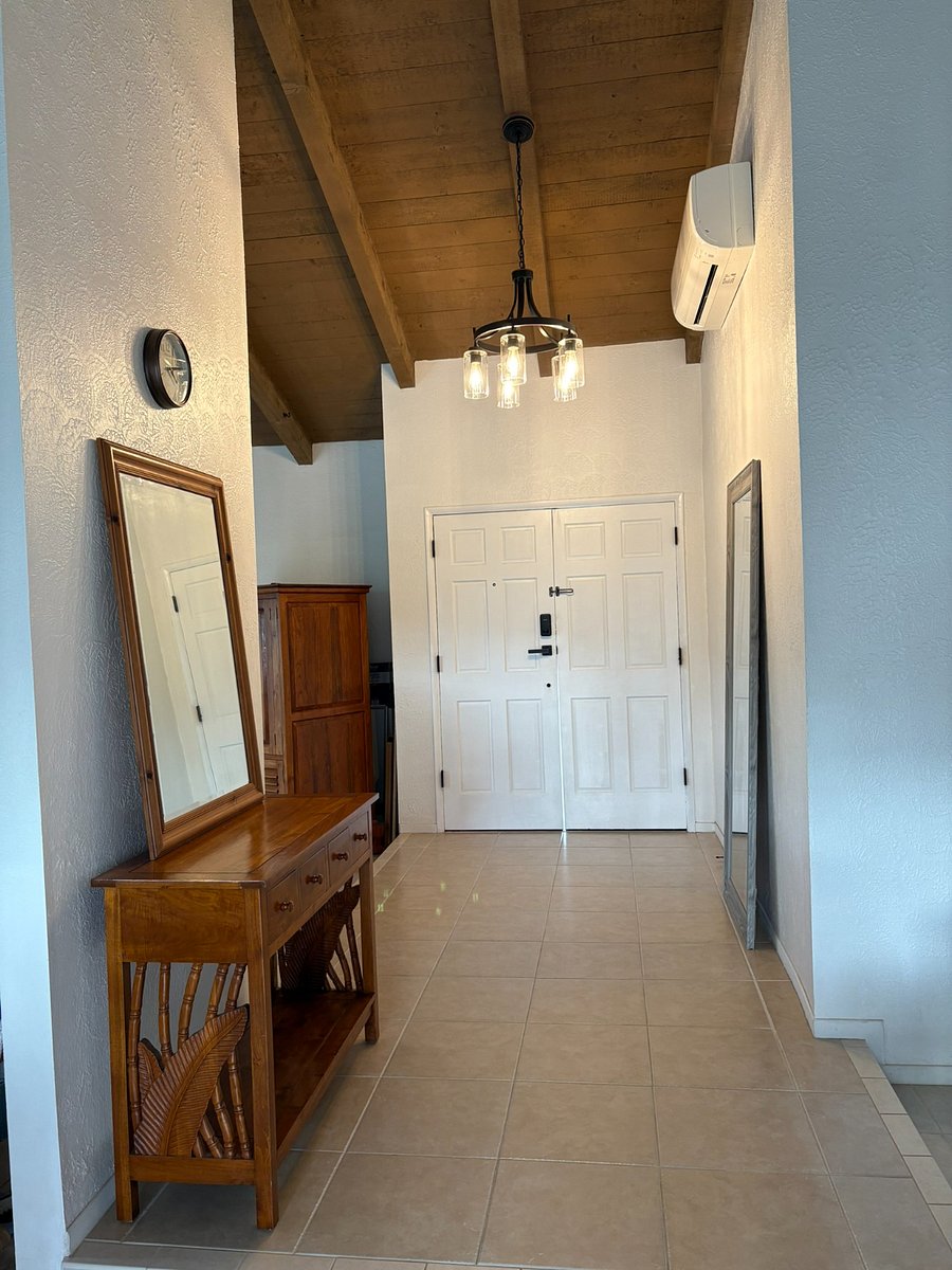 Foyer: 1 banana leaf teak console table, 1 medium size tan beveled mirror, 1 clock, 1 large full length gray entryway mirror, 1 foyer chandelier, 1 Mitsubishi split AC with remote control.