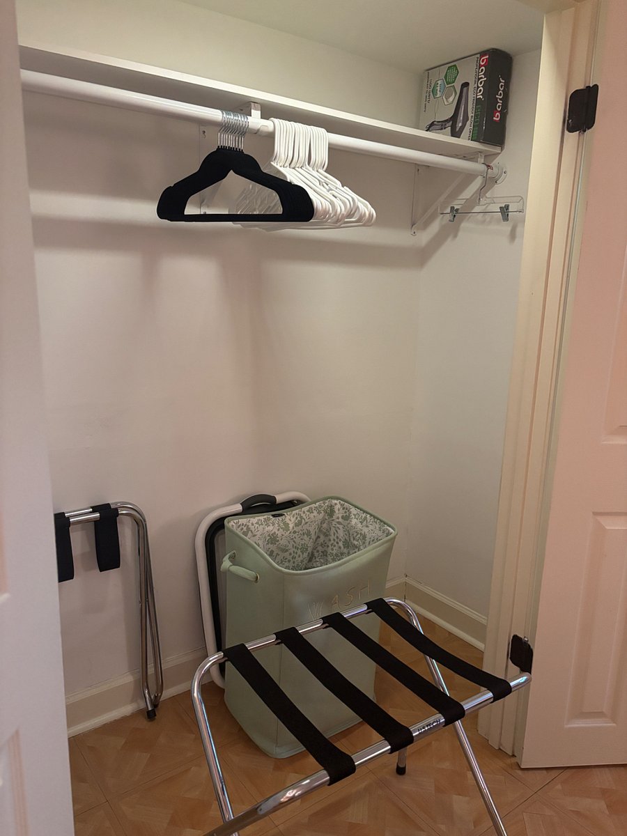 View of the inside of the closet. Lanundry basket, laundry hamper, luggage rack, hair dryer and hangers.