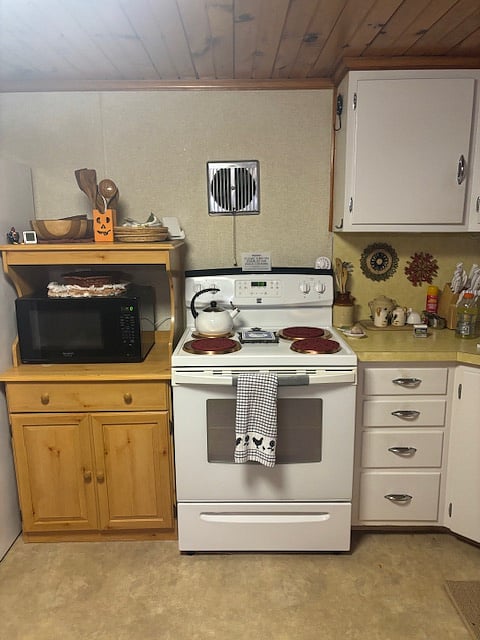 Electric over and stove, microwave. Drinking cups to the right of the stove. 