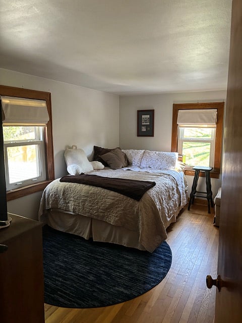 Guest room with a queen size Sealy bed and medium darkening roman blinds.