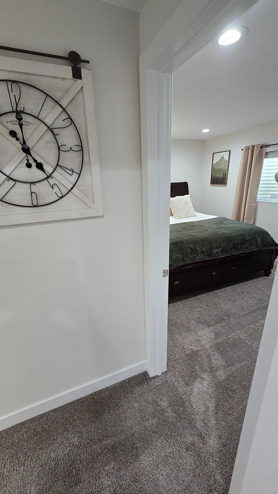 As you leave the kitchen, you'll see this large clock. To your right, the primary bedroom. To the left, you'll find your spacious and bright living room.