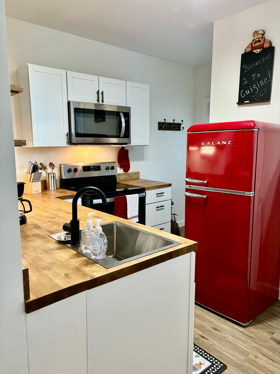 Kitchen features retro fridge with top freezer. Stove, microwave, dishwasher, coffee pot and toaster. Stocked with dishes, glasses, pots and pans.