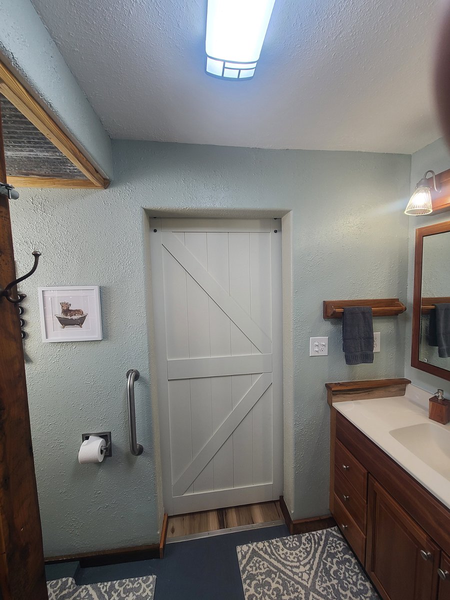 Sliding barn door and barn theme throughout the bathroom with milk house glass shower.
