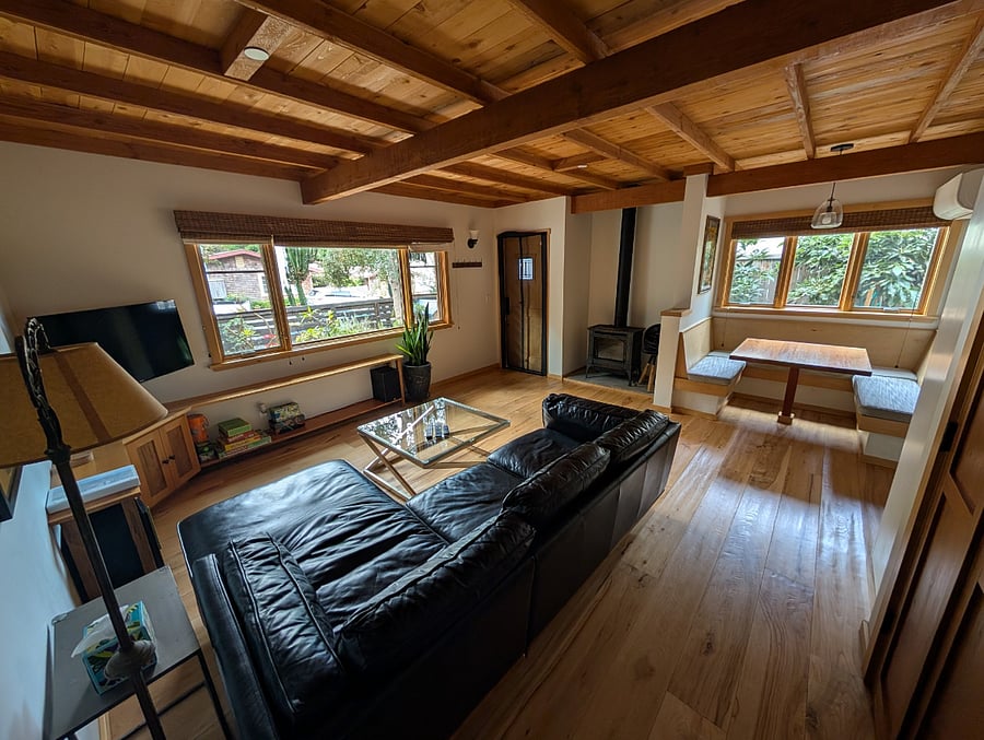 Current picture of the living room with black leather sectional couch and glass coffee table