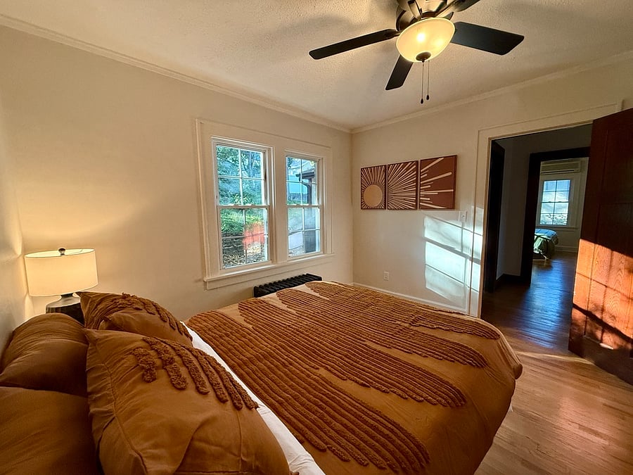 Second Bedroom with Queen Bed, En-Suite Full Bathroom, Walk-In Closet, Black Out Curtains, Dresser, Nightstand, and Bedside Lamp.