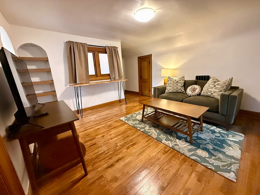 Living room with high-top table seating (stools not in photo), desk for dedicated work space, and built in shelves. 