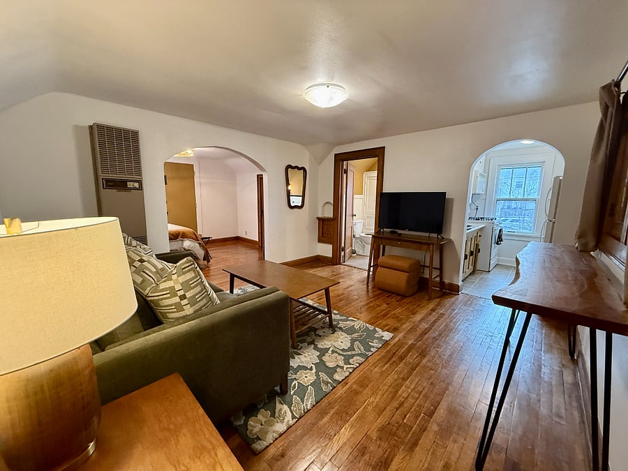 Living Room looking towards the Kitchen (right archway), Full bathroom (left of TV), and Bedroom (left archway).