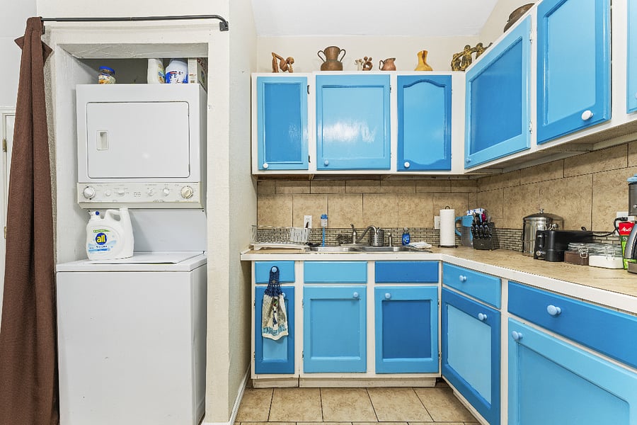 Partial kitchen view with view of stacked washer/dryer (usually hidden from view by curtain)