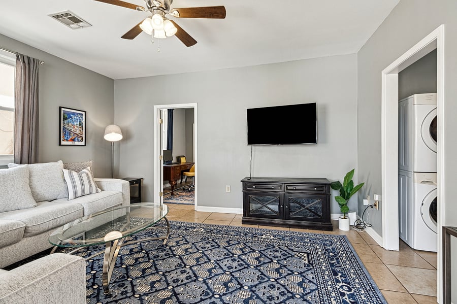 The cozy living room is flooded with natural light. A sectional allows for ample, comfy seating around the smart TV.